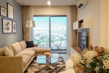 Apartment living room with couch, rug, coffee table, plant, and flower arrangement.