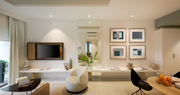 Apartment living room with television, white wooden media console, and brown modern interior styling.
