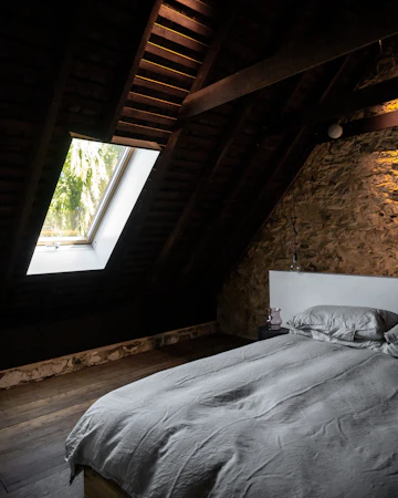 Attic bedroom with bed, wood flooring, window, and interior furnishings.