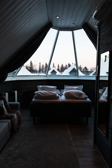 Bedroom with bed, large window, couch, wood floor, and loft-style interior.