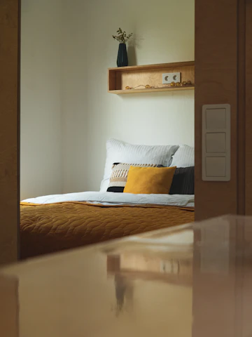 Light-colored bedroom with bed, soft daylight, neutral decor, and window.