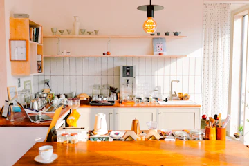 Lived-in kitchen with window, wood furniture, coffee, laptop, and dining table.