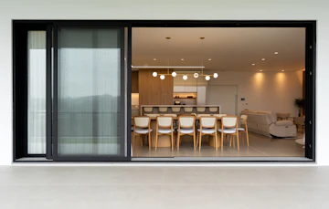 Modern dining room with chairs, dining table, sofa, kitchen island, and natural light.
