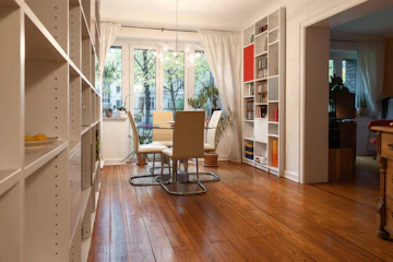 Dining room with table, chairs, ceiling-high shelving, wood details, and plant decor.